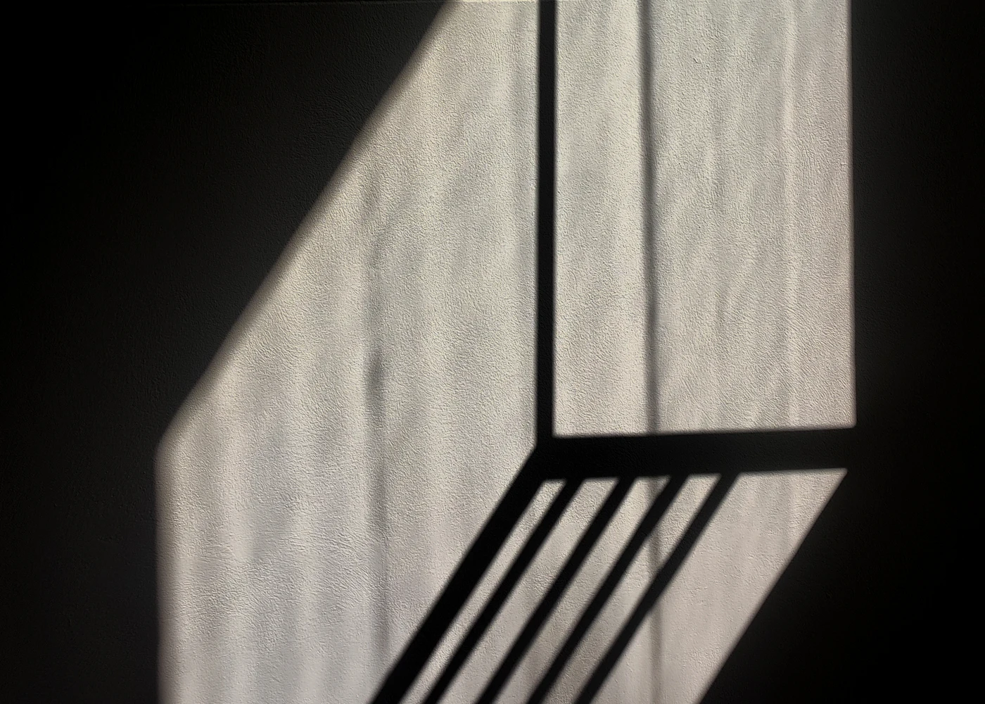 Sharp architectural shadow falling across a plain wall