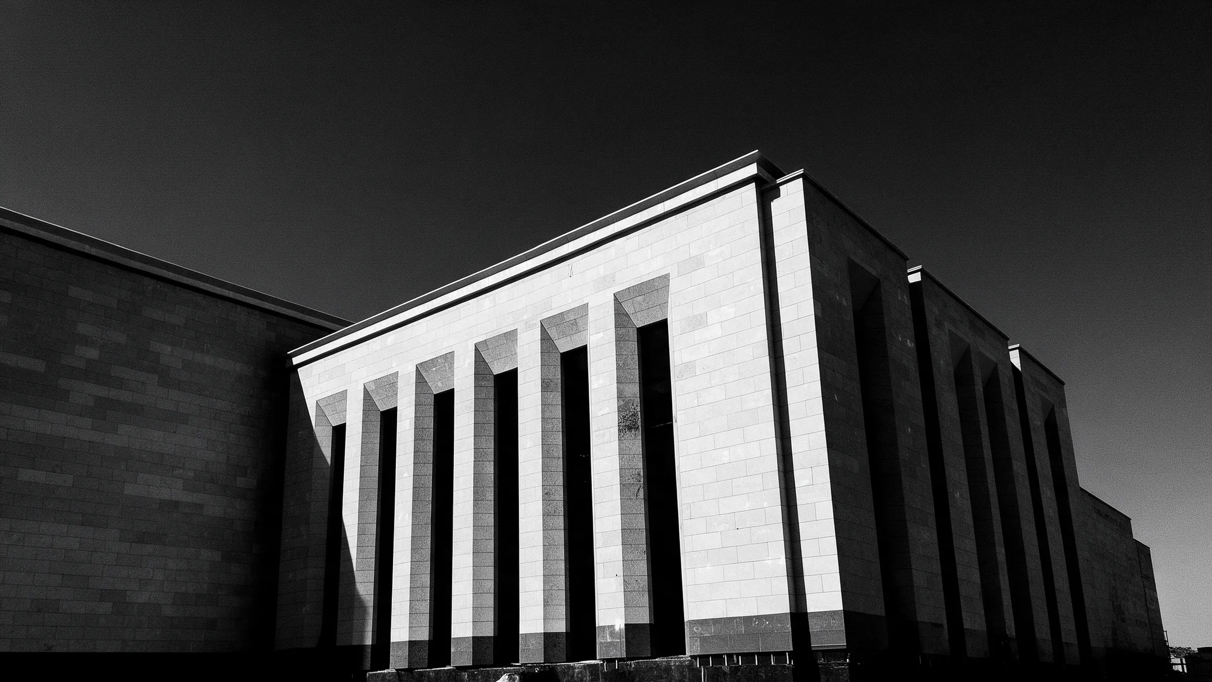 Monumental stone-clad elevation with deep vertical fins