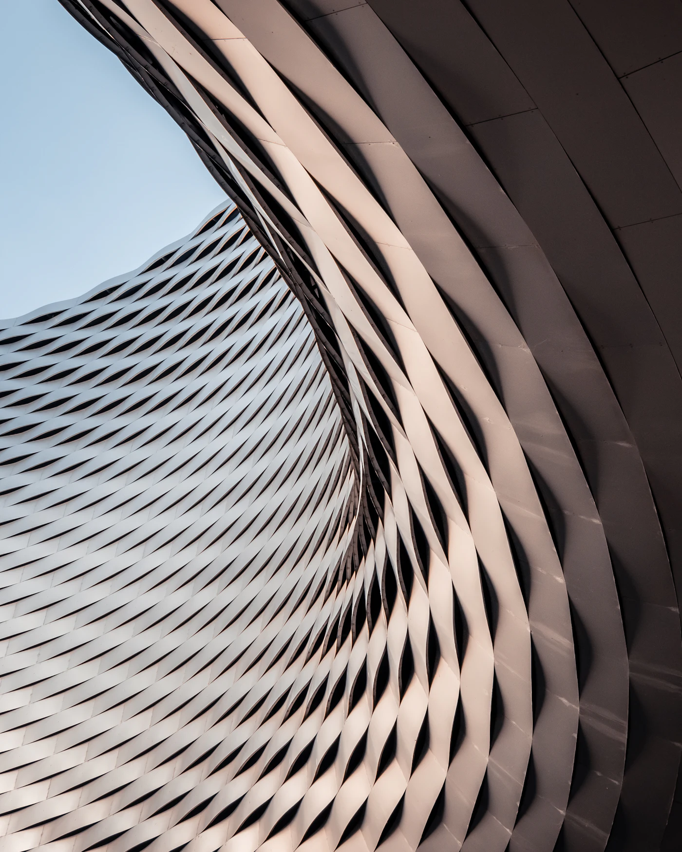 Curved perforated façade skin in mineral tones